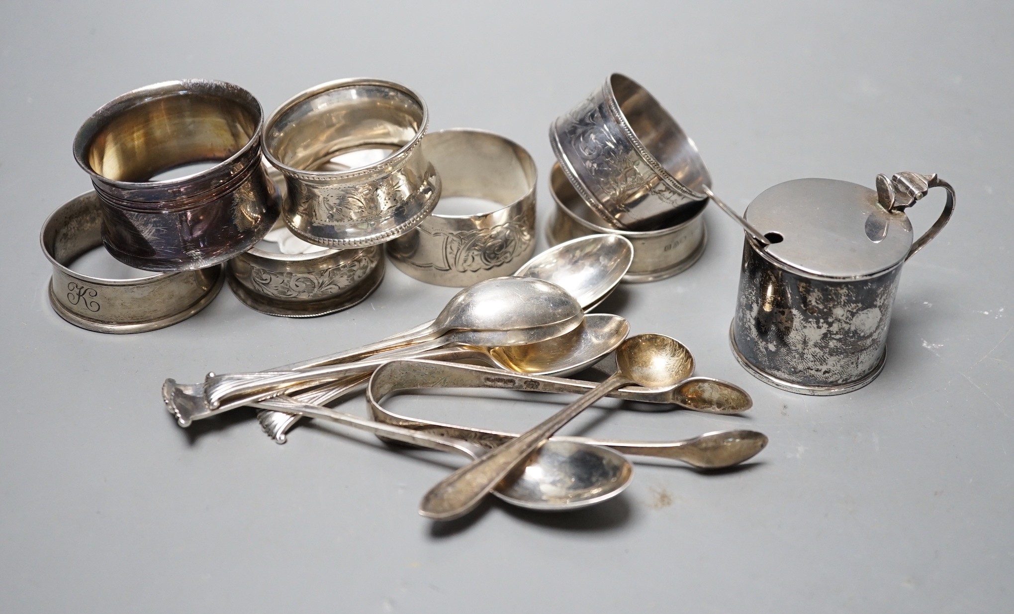 An Edwardian silver mustard pot, Birmingham, 1905, a set of six 'Onslow' pattern silver teaspoons by William Hutton & Sons, London, 1903, a pair of silver sugar tongs, a silver condiment spoons, six assorted silver napki
